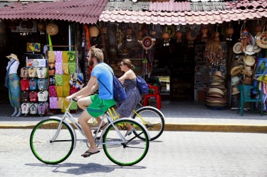 Visitors bike past shops in downtown Tulum, Mexico.