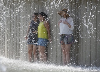 Tourists cool off in a public fountain at the Sforzesco Castle, in Milan, Italy.  Europe's heat wave has pushed the ...