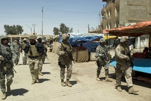 File - Members of Multi-National Forces - West walk through the market district of Hit, Iraq, April 25, 2007, prior to attending an Al Anbar Provincial Council meeting.