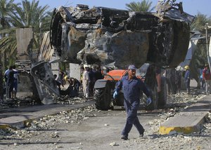 Civilians and security forces gather as municipality workers remove destroyed vehicles at the scene of a deadly suicide bomb attack in Hillah, about 60 miles (95 kilometers) south of Baghdad, Iraq, Sunday, March 6, 2016.