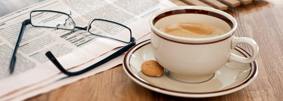 Newspaper with glasses and a cup of brewed coffee