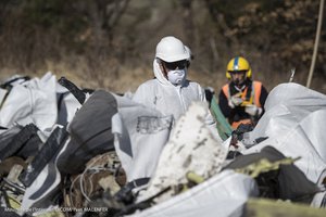 File - In this photo provided Monday, April 13, 2015 by the French Interior Ministry, rescue workers stand among bags filled with debris of the Germanwings passenger jet, gathered near the crash site in Seyne-les-Alpes, France.