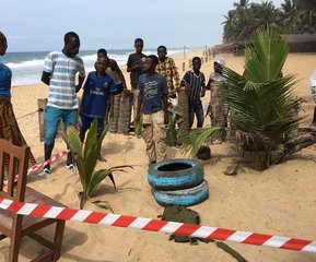 Local people stand near a taped off area that formed part of the crime scene outside the Nouvelle Paillote Hotel, one of the three hotels involved in an attack at Grand Bassam, Ivory Coast, Monday, March 14, 2016.