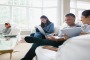 Family using wireless technology on living room sofa