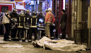 Rescue workers gather at victims in the 10th district of Paris, Friday, Nov. 13, 2015. More than 120 people were killed in a series of unprecedented attacks around Paris on Friday.