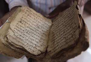 In this Tuesday, Jan. 27, 2015, file photo, a man holds an ancient manuscript that will need to be restored after being damaged in Bamako, Mali.