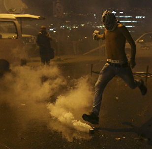 A Lebanese anti-government protester kicks back a tear gas canister shot by security forces during a protest against the ongoing trash crisis and government corruption, in downtown Beirut, Lebanon, Thursday, Oct. 8, 2015. Lebanese security forces used water cannons and eventually fired tear gas canisters to disperse dozens of anti-government protesters who tried to get past security barricades and reach parliament.