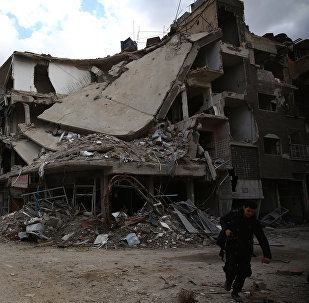 A photographer walks in the neighbourhood of Jobar, on the eastern outskirts of the capital Damascus, on January 23, 2016