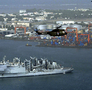 Helicopter flies over Djibouti harbour as part of city is seen, background