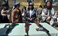 Former Taliban fighters look on as they stand alongside their weapons in Jalalabad, the capital of Nangarhar province on March 19, 2014