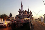 In this file photo taken Monday, June 23, 2014, fighters from the Islamic State group parade in a commandeered Iraqi security forces armored vehicle down a main road at the northern city of Mosul, Iraq.