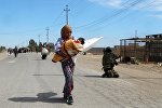 A woman carrying her child makes flees to safe areas with help from Iraqi security forces, west of Ramadi, March 9, 2016