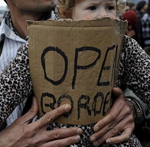 A stranded refugee holds a child during a protest at the Greek-Macedonian border as they wait for the border crossing to reopen near the Greek village of Idomeni, February 28, 2016.