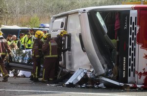 Emergency services personnel stand at the scene of a bus accident crashed on the AP7 highway that links Spain with France along the Mediterranean coast near Freginals halfway between Valencia and Barcelona early Sunday, March 20, 2016.