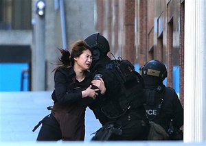 A hostage runs to armed tactical response police officers for safety after she escaped from a cafe under siege at Martin Place in the central business district of Sydney, Australia, Monday, Dec. 15, 2014.