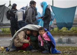 Children take shelter from the rain in Sredisce ob Dravi, a border crossing between Croatia and Slovenia Monday, Oct. 19, 2015.