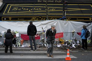 A man walks in front of the Bataclan concert hall in Paris as people pay respect to the victims a week after the start of the Paris attacks, Sunday, Nov. 22, 2015.