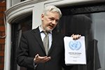 WikiLeaks founder Julian Assange holds a copy of a U.N. ruling as he makes a speech from the balcony of the Ecuadorian Embassy, in central London, Britain February 5, 2016.