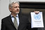 WikiLeaks founder Julian Assange holds a copy of a U.N. ruling as he makes a speech from the balcony of the Ecuadorian Embassy, in central London, Britain February 5, 2016.