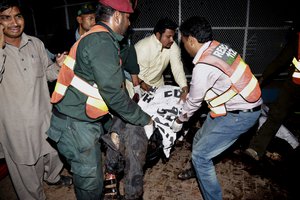 Pakistani rescue workers remove a dead body from the site of bomb explosion in a park in Lahore, Pakistan, Sunday, March, 27, 2016.