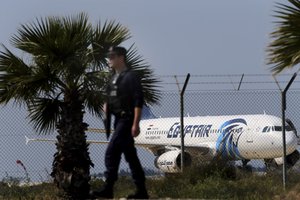 A police officer patrol outside from the airport as in the background seen on the ground the hijacked aircraft of Egyptair after landing at Larnaca airport Tuesday, March 29, 2016.