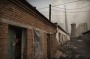 A Chinese worker looks out from his house next to a coal-fired power plant on the outskirts of Beijing. China has set ...