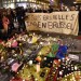 People holding a banner reading "I am Brussels" behind flowers and candles to mourn for the victims at Place de la Bourse in the centre of Brussels.