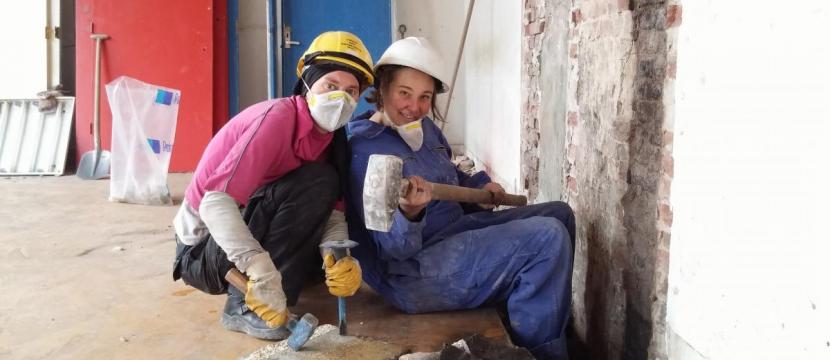 Two volunteers are taking down left overs of the chimney on a work weekend.