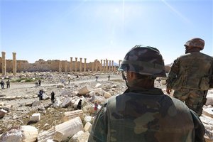 In this picture taken Friday, April 1, 2016, soldiers look over damage at the historical Bel Temple in the ancient city of Palmyra in the central city of Homs, Syria.