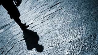 Shadow of man standing on pavement after dark