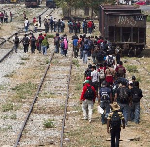 Immigrants walk along the rail tracks after getting off a train during their journey toward the US-Mexico border in Ixtepec, southern Mexico