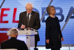 File - Democratic presidential candidate, Hillary Clinton enters the stage after a break as Democratic presidential candidate, Sen. Bernie Sanders, I-Vt, makes notes, during the Univision, Washington Post Democratic presidential debate at Miami-Dade College, Wednesday, March 9, 2016, in Miami, Fla.