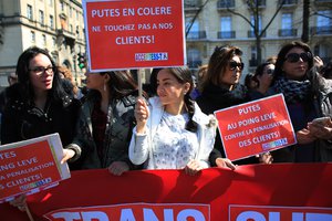 Sex workers hold signs reading 'Prostitutes are angry. Don't touch to our customers' during a protest against new bill against prostitution and sex trafficking, in Paris, Wednesday, April 6, 2016.