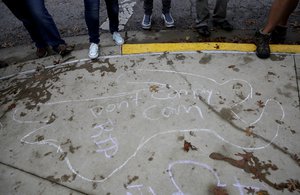 Counter protesters stand on a chalk out-line drawing of a body at the University of Texas where a gun rights activist group staged a mock mass shooting, Saturday, Dec. 12, 2015, in Austin, Texas.