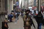 In this image taken from TV an armed member of the security forces stands guard as emergency services attend the scene after a explosion in a main metro station in Brussels on Tuesday, March 22, 2016