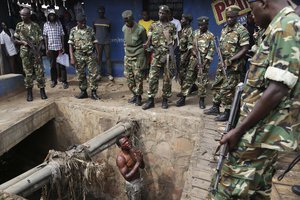 File - Jean Claude Niyonzima, a suspected member of the ruling party's Imbonerakure youth militia, pleads with soldiers to protect him from a mob of demonstrators after he came out of a sewer in the Cibitoke district of Bujumbura, Burundi, Thursday, May 7, 2015.