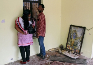 A couple stands next to a picture of a Hindu deity after a fire broke out at a temple in Kollam...