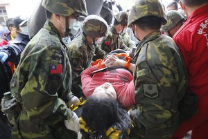 Rescue workers remove a victim from a collapsed building from an early morning earthquake in Tainan, Taiwan, Saturday, Feb. 6, 2016. A 6.4-magnitude earthquake struck southern Taiwan early Saturday, toppling at least one high-rise residential building and trapping people inside. (AP Photo/Wally Santana)