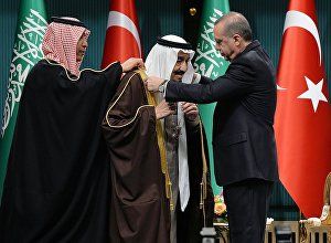 Turkish President Recep Tayyip Erdogan (R) presents Turkey's highest state medal to King Salman of Saudi Arabia (C) during a ceremony at the presidential complex in Ankara on April 12, 2016