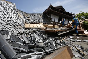 Police rescue team members search through damaged houses to check possibility of trapped people in Mashiki, Kumamoto prefecture, southern Japan, Friday, April 15, 2016.