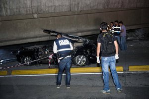 Police look at a car crushed under a collapsed overpass in Guayaquil, Ecuador, Saturday April 16, 2016. The strongest earthquake to hit Ecuador in decades flattened buildings and buckled highways along the country's coast, killing at least 41 people.