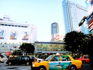 Busy road filled with vehicles, and rows of multimedia-clad buildings on in Tokyo, Japan.