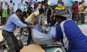 Volunteers rescue a body from a destroyed building after an earthquake in Pedernales, Ecuador, Sunday, April 17, 2016.