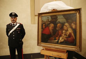 An Italian Carabinieri paramilitary police officer stands next to a painting "Circumcision of Jesus at Temple", attributed to early Renaissance painter Girolamo dai Libri, during a press conference on recovered paintings seized by the Nazis in 1944 in Camaiore near Lucca, Italy, at the Brera Art Gallery, in Milan, Italy, Monday, April 18, 2016.