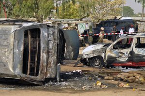 In this Tuesday Feb. 24, 2015 file photo, police officers stand guard following a suicide bomb explosion at a bus station in Kano, Nigeria. The number of child bombers used by the Islamic extremists of Boko Haram has increased 10-fold in a year with devastating consequences in communities that now see children as threats.