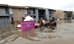 Evacuees wade through floodwaters surrounding their apartment complex Monday, April 18, 2016, in Houston. Storms have dumped more than a foot of rain in the Houston area