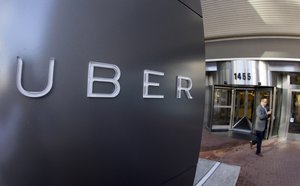 FILE - In this Dec. 16, 2014, file photo a man leaves the headquarters of Uber in San Francisco. The ride-hailing company said Thursday, April 7, 2016 it will pay at least $10 million to settle a case in which California prosecutors alleged it misled passengers over the quality of its driver background checks.