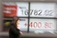 A woman walks past an electronic stock board at a securities firm