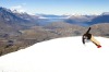 A snowboarder blasts a heel side turn while snowboarding in Queenstown, New Zealand.