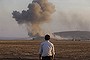 A Turkish Kurd watches as airstrikes hit Kobani, inside Syria, as fighting intensifies between Syrian Kurds and the militants of Islamic State group, in Mursitpinar, on the outskirts of Suruc, at the Turkey-Syria border, Wednesday, Oct. 8, 2014. Kobani, also known as Ayn Arab and its surrounding areas have been under attack since mid-September, with militants capturing dozens of nearby Kurdish villages. (AP Photo/Lefteris Pitarakis)